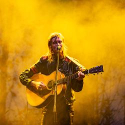 Anna Ternheim, steht in dichtem Nebel vor einem Mikrofon und spielt Gitarre. Sie wird mit warmen, gelben Licht angestrahlt.