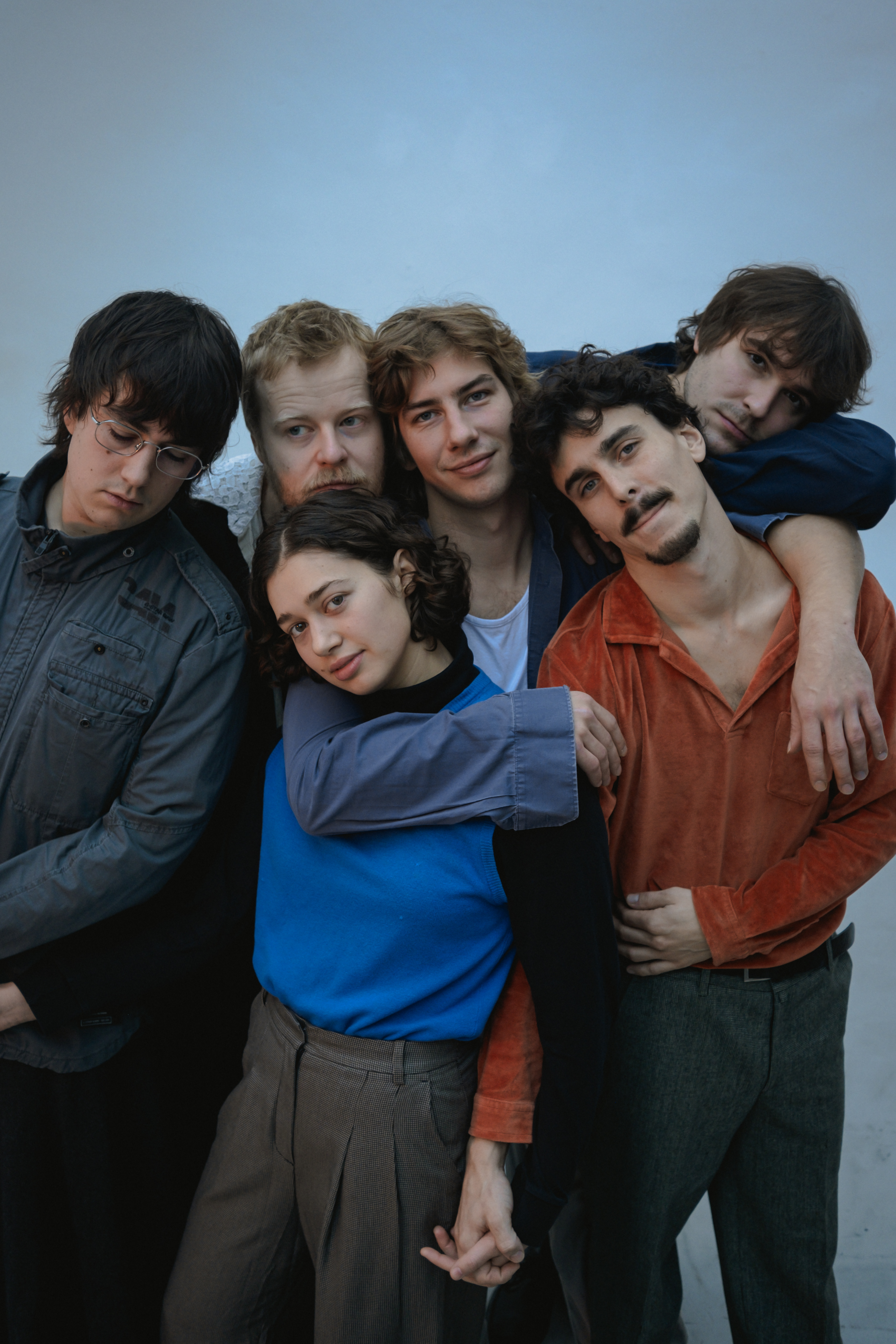 Die 6 Mitglieder der Band Bundspecht stehen alle eng beieinander. Sie haben entweder die Arme umeinander gelegt oder halten sich an der Hand. Alle blicken direkt in die Kamera. Nur der außen links hat seinen Blick auf den Boden gerichtet.